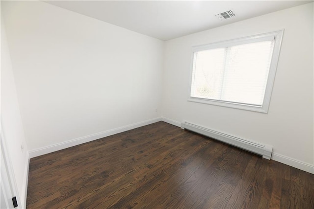 empty room with baseboard heating, baseboards, dark wood-type flooring, and visible vents