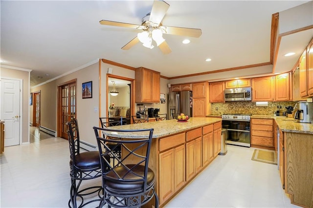 kitchen featuring light stone counters, a baseboard heating unit, a kitchen island, backsplash, and appliances with stainless steel finishes