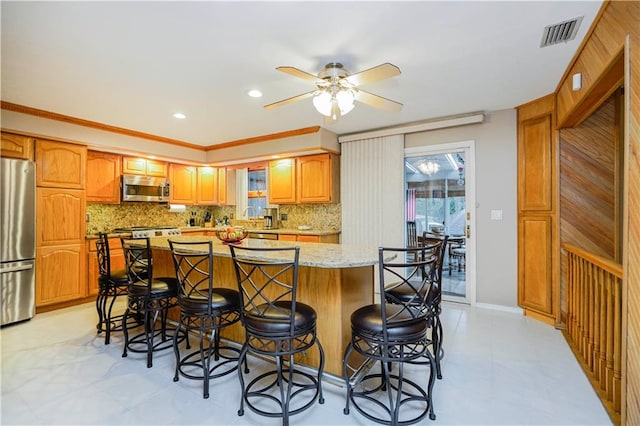 kitchen with a kitchen bar, tasteful backsplash, visible vents, and appliances with stainless steel finishes