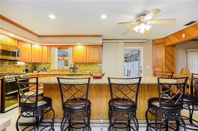 kitchen with visible vents, a sink, stainless steel appliances, backsplash, and a center island