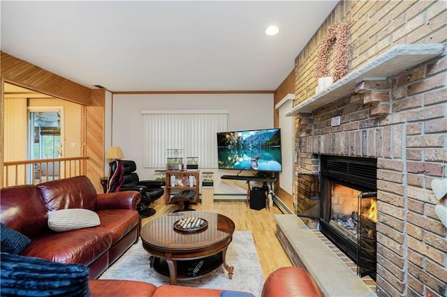 living area with ornamental molding, a fireplace, a baseboard heating unit, and wood finished floors