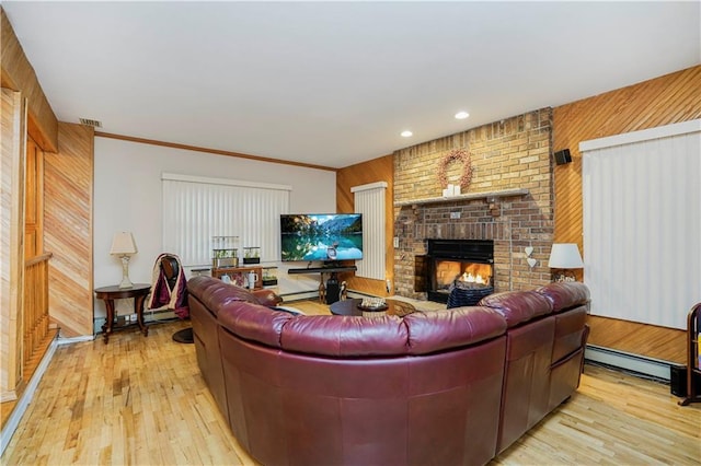 living room featuring baseboard heating, a fireplace, light wood-type flooring, and wooden walls