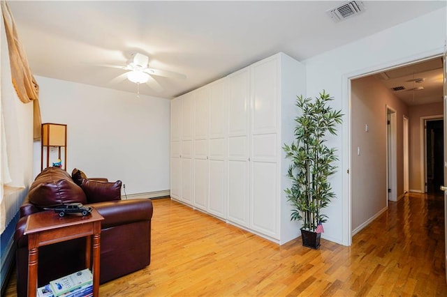 living area with a baseboard radiator, ceiling fan, visible vents, and light wood-type flooring