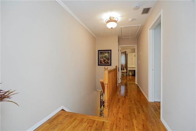 hall with visible vents, an upstairs landing, attic access, and light wood finished floors