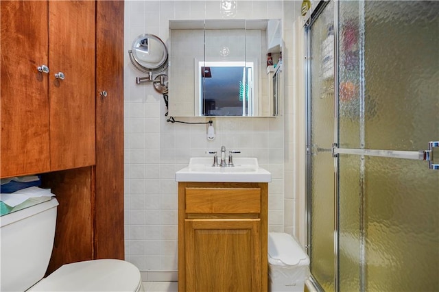 bathroom with vanity, tile walls, toilet, and a stall shower