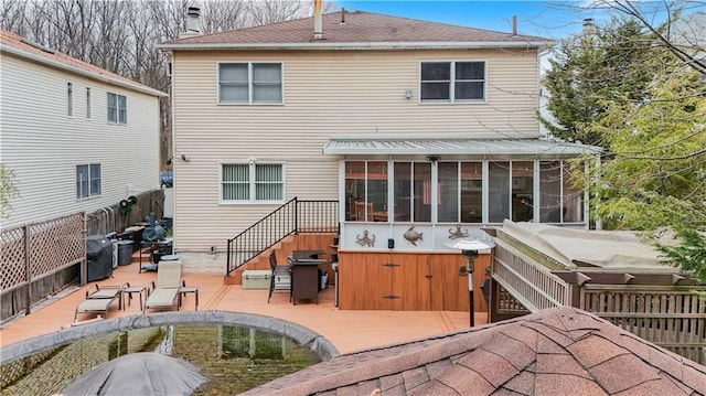 back of property with a deck, a patio, fence, a sunroom, and a chimney