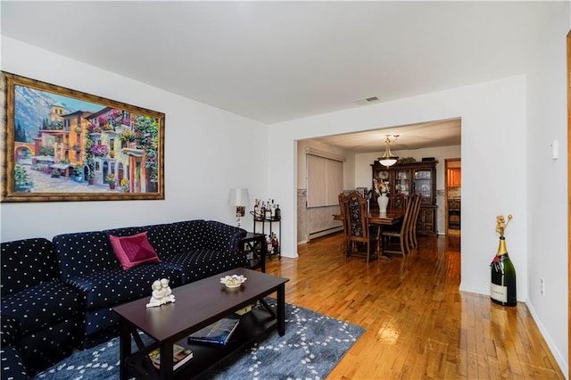 living area featuring hardwood / wood-style flooring, baseboards, visible vents, and baseboard heating