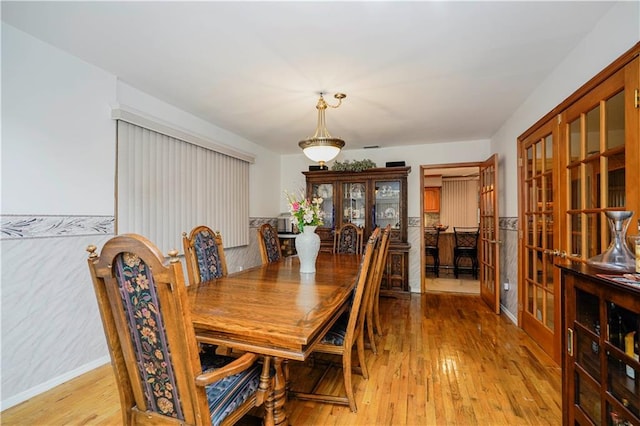 dining room featuring french doors, baseboards, and light wood finished floors