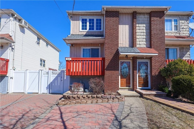 view of front of property with decorative driveway, brick siding, and a gate