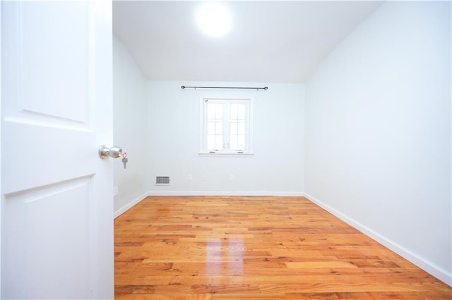 unfurnished room featuring light wood-type flooring, visible vents, and baseboards