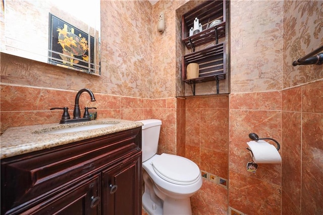 bathroom featuring vanity, tile walls, and toilet