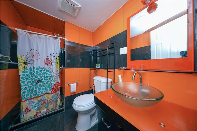 bathroom featuring toilet, a shower with shower curtain, vanity, tile patterned floors, and tile walls