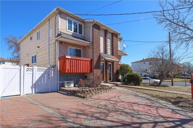 view of front of property with ac unit, fence, brick siding, and a gate