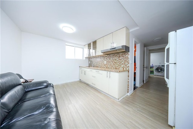 unfurnished living room featuring washer / clothes dryer, baseboards, light wood-type flooring, and a sink