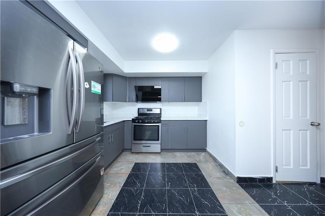 kitchen featuring baseboards, light countertops, gray cabinets, appliances with stainless steel finishes, and marble finish floor