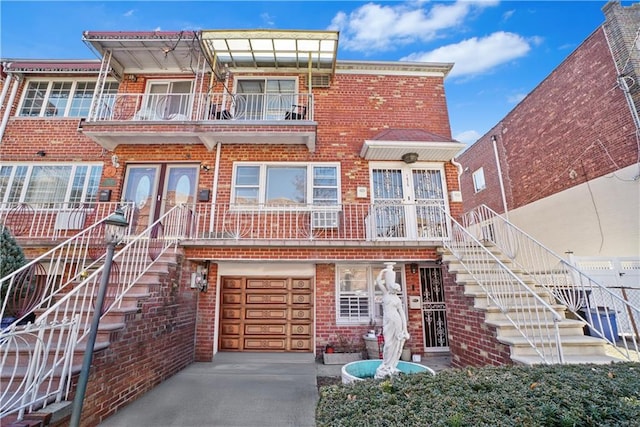 multi unit property featuring stairs, concrete driveway, french doors, a garage, and brick siding