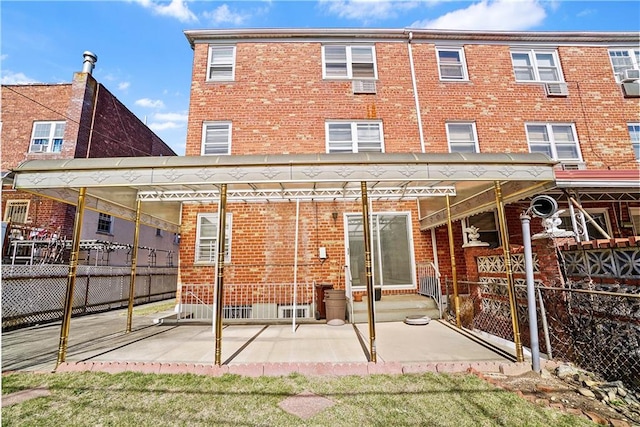 rear view of house with brick siding, a patio area, and fence