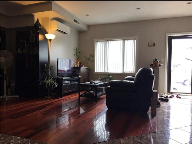 living area featuring visible vents, wood finished floors, and an AC wall unit