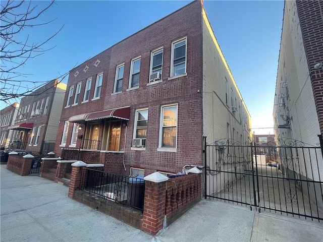 view of front of property featuring brick siding, cooling unit, a gate, and fence