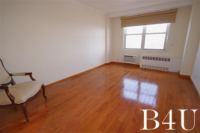 empty room featuring crown molding, radiator, baseboards, a wall mounted AC, and hardwood / wood-style flooring