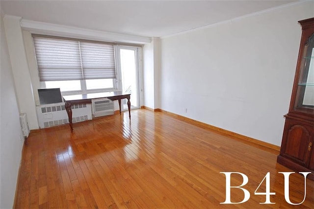 empty room with radiator heating unit, crown molding, a wall mounted AC, and light wood finished floors