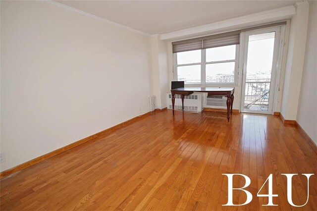 empty room featuring crown molding, radiator heating unit, baseboards, and light wood-style flooring