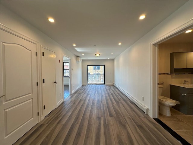 unfurnished room featuring dark wood-type flooring, baseboards, recessed lighting, a wall mounted AC, and a sink