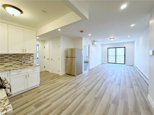 kitchen featuring a baseboard heating unit, open floor plan, an AC wall unit, decorative backsplash, and appliances with stainless steel finishes