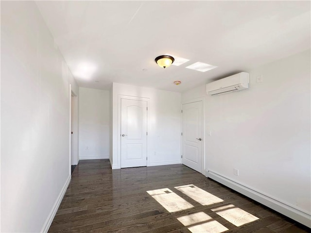 spare room featuring a wall mounted air conditioner, a baseboard heating unit, baseboards, and dark wood-style flooring