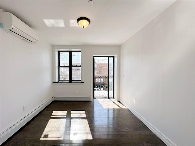 spare room featuring a baseboard heating unit, a wall unit AC, wood finished floors, and baseboards