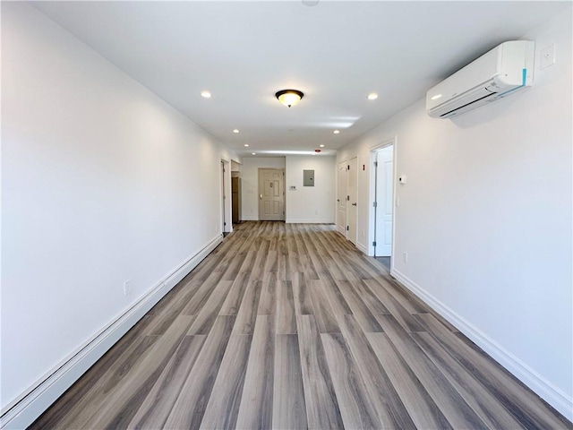 hallway with recessed lighting, a wall mounted air conditioner, light wood-type flooring, and baseboards