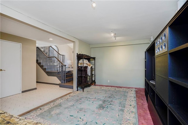 interior space featuring stairway, baseboards, and track lighting