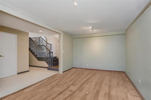 empty room with stairs, baseboards, and wood finished floors