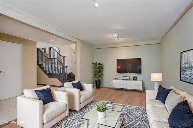 living area with stairway, wood finished floors, and track lighting