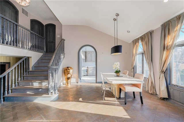 dining area featuring visible vents, arched walkways, high vaulted ceiling, and stairway