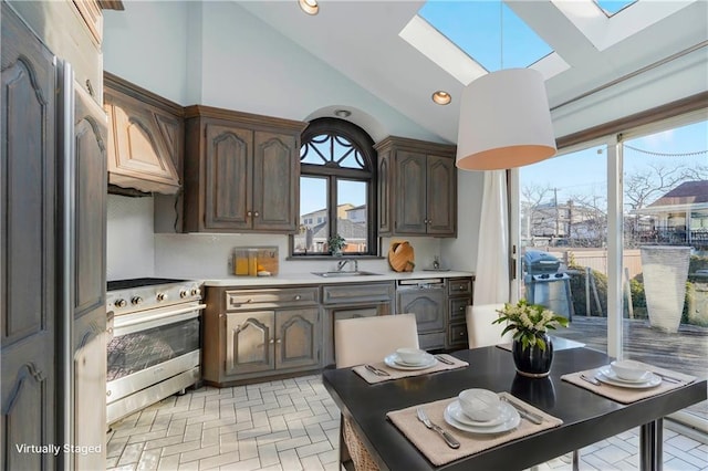 kitchen with a skylight, a sink, light countertops, stainless steel range oven, and dishwasher