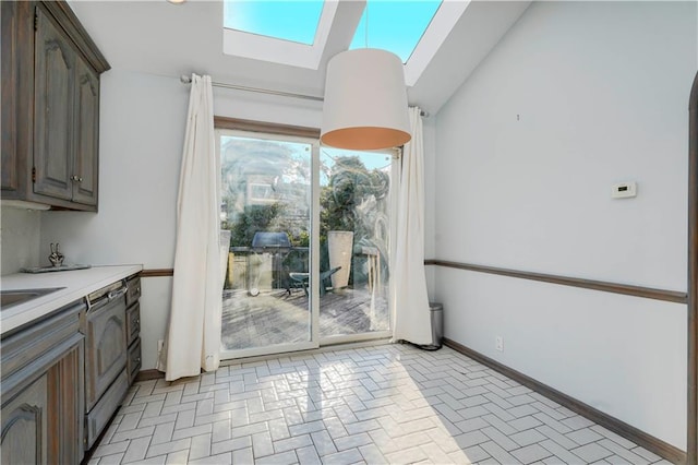 interior space featuring lofted ceiling with skylight, brick floor, and baseboards