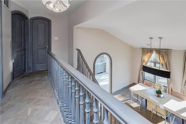 corridor with visible vents, baseboards, a chandelier, vaulted ceiling, and arched walkways