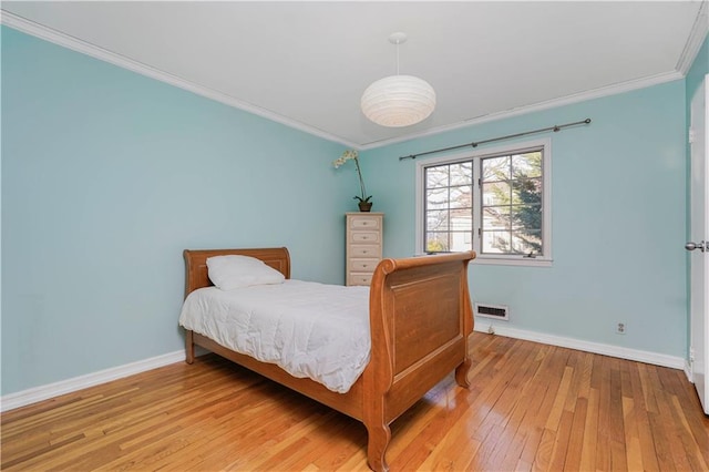 bedroom featuring visible vents, baseboards, ornamental molding, and hardwood / wood-style flooring