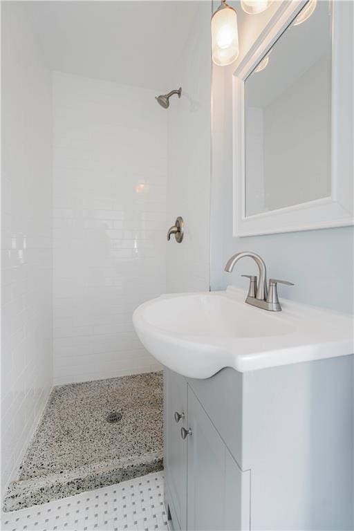 bathroom with tiled shower and vanity