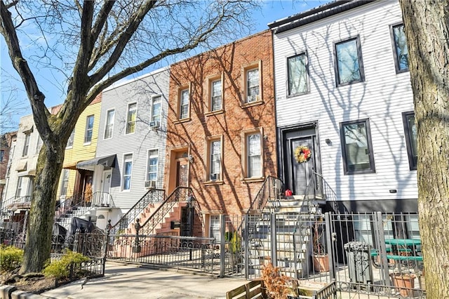 townhome / multi-family property with brick siding, a residential view, a fenced front yard, and a gate