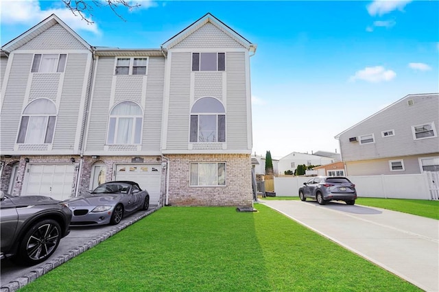 view of property featuring fence, driveway, a front lawn, a garage, and brick siding