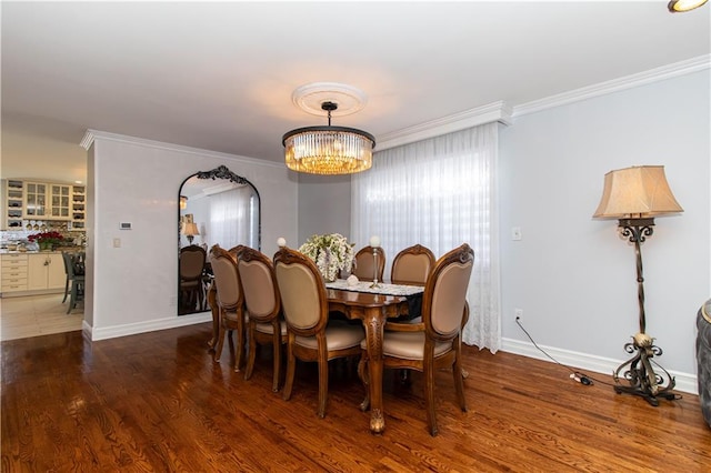 dining space with a wealth of natural light, a notable chandelier, ornamental molding, and wood finished floors