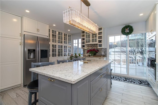 kitchen featuring stainless steel fridge with ice dispenser, light stone counters, decorative backsplash, gray cabinets, and white cabinetry