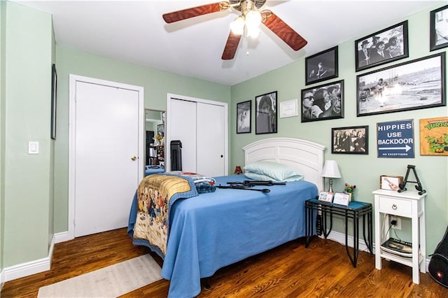 bedroom featuring a ceiling fan, wood finished floors, baseboards, and two closets