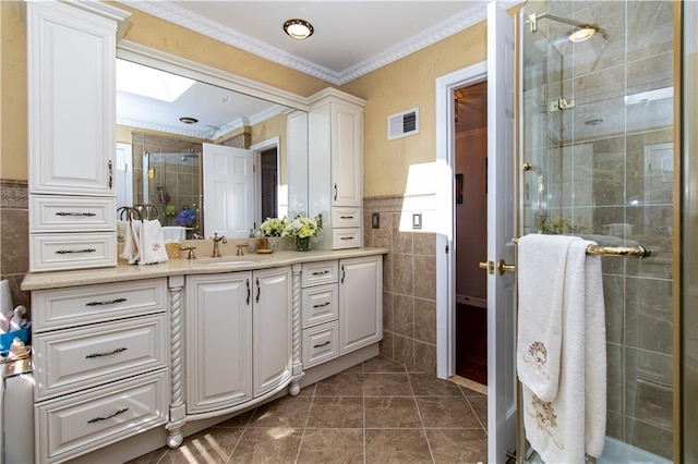 bathroom featuring vanity, a skylight, ornamental molding, a shower stall, and tile walls