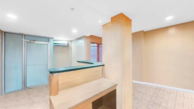 interior space featuring recessed lighting, light floors, an AC wall unit, and baseboards