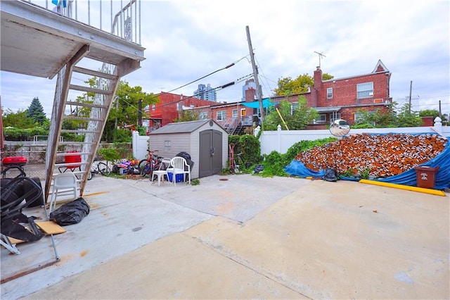 view of patio with an outdoor structure, a fenced backyard, and a shed