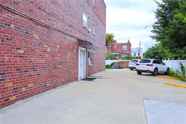 8784 24th Ave, Brooklyn, NY 11214 - view of property exterior featuring brick siding, uncovered parking, and fence