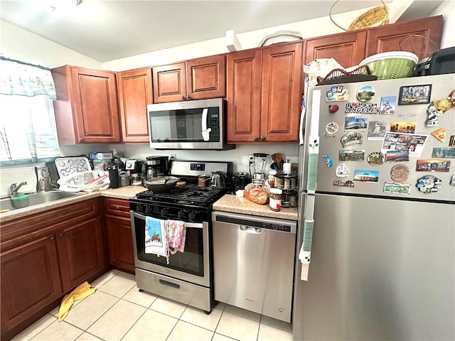 kitchen featuring light tile patterned flooring, appliances with stainless steel finishes, light countertops, and a sink